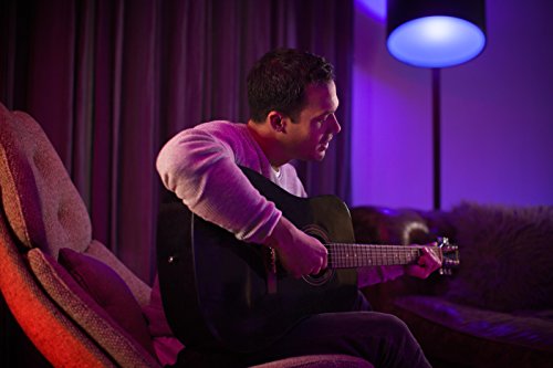 man plays guitar in room with colored light